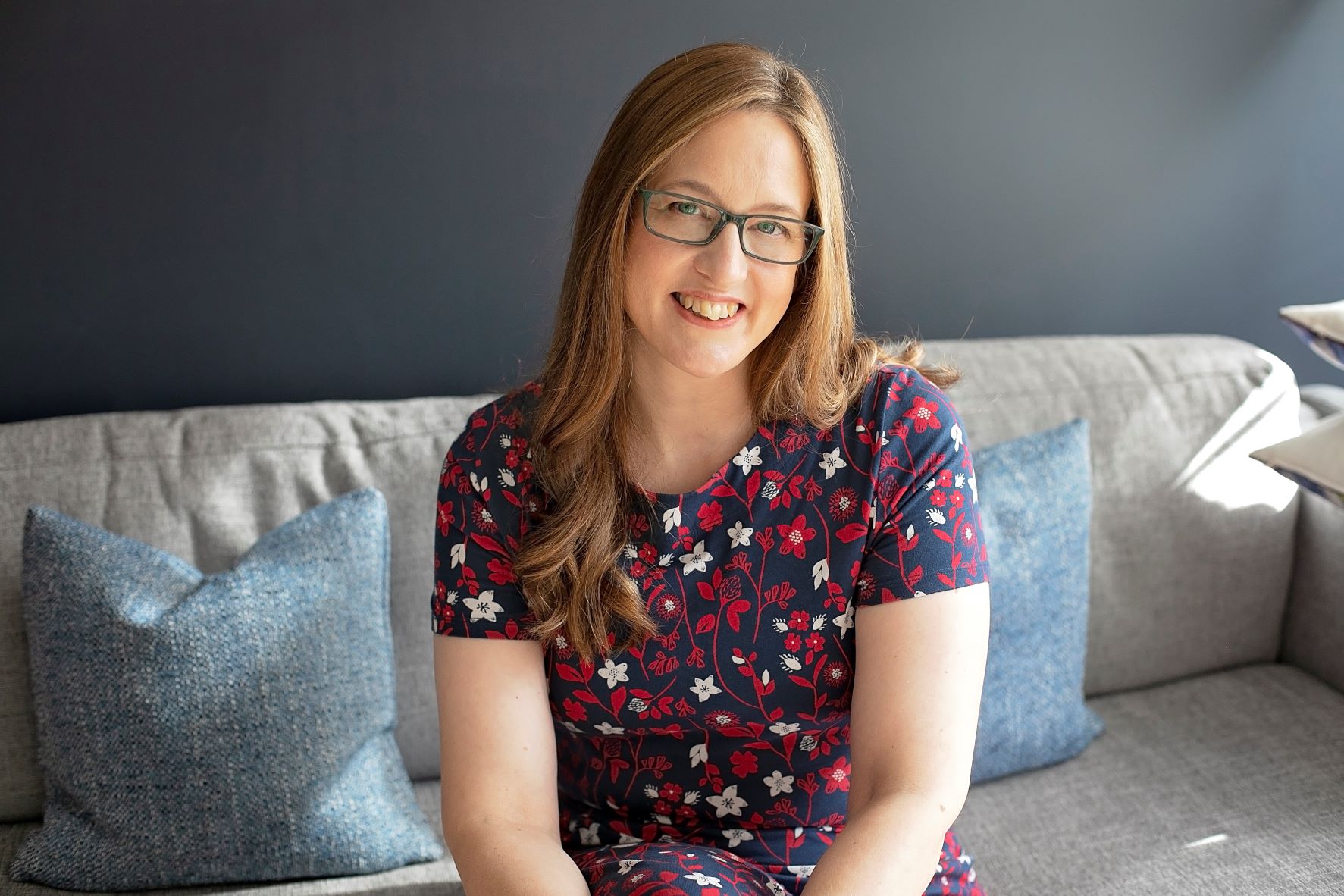 Liz sitting on a sofa, smiling at the camera
